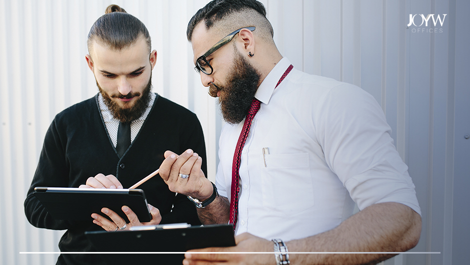 Dos hombres de mediana edad, tez blanca, con barba, analizando algo en una tablet