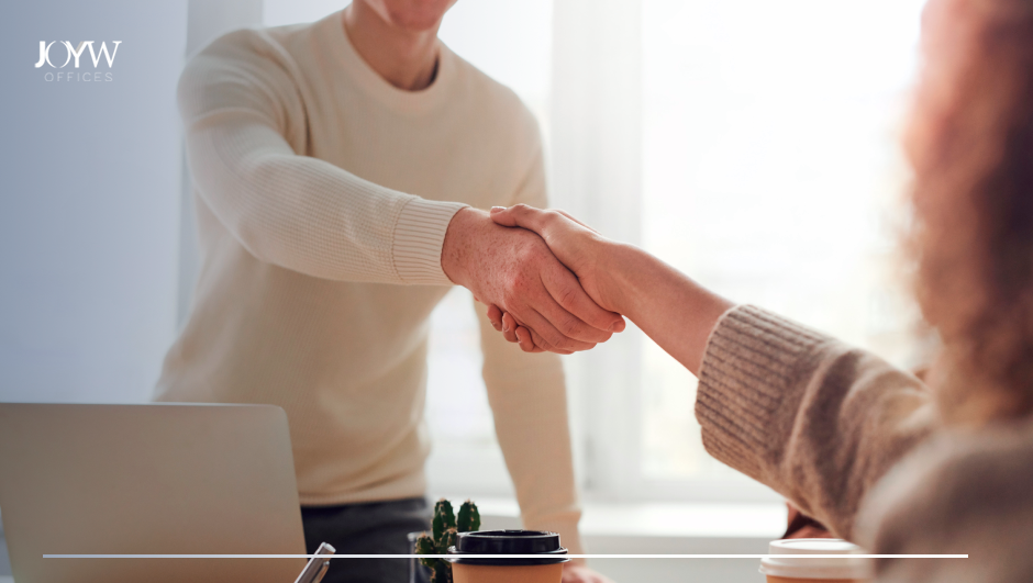dos compañeros de trabajo se dan la mano para mejorar el ambiente laboral